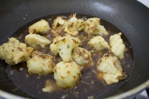 Adding florets to the sauce mixtures and saute it