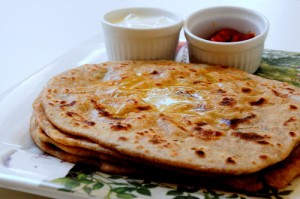 Spicy Aloo Paratha served with curd and pickles with butter topping
