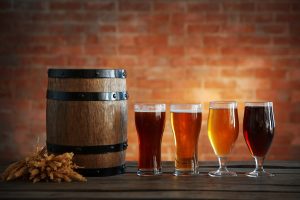 Glasses with different sorts of craft beer, wooden barrel and bar